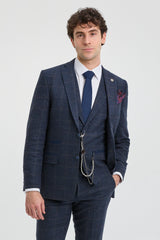 Άνδρας που φοράει μπλε καρό κοστούμι με λευκό πουκάμισο και μπλε γραβάτα σε ανοιχτό γκρι φόντο