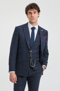 Άνδρας που φοράει μπλε καρό κοστούμι με λευκό πουκάμισο και μπλε γραβάτα σε ανοιχτό γκρι φόντο